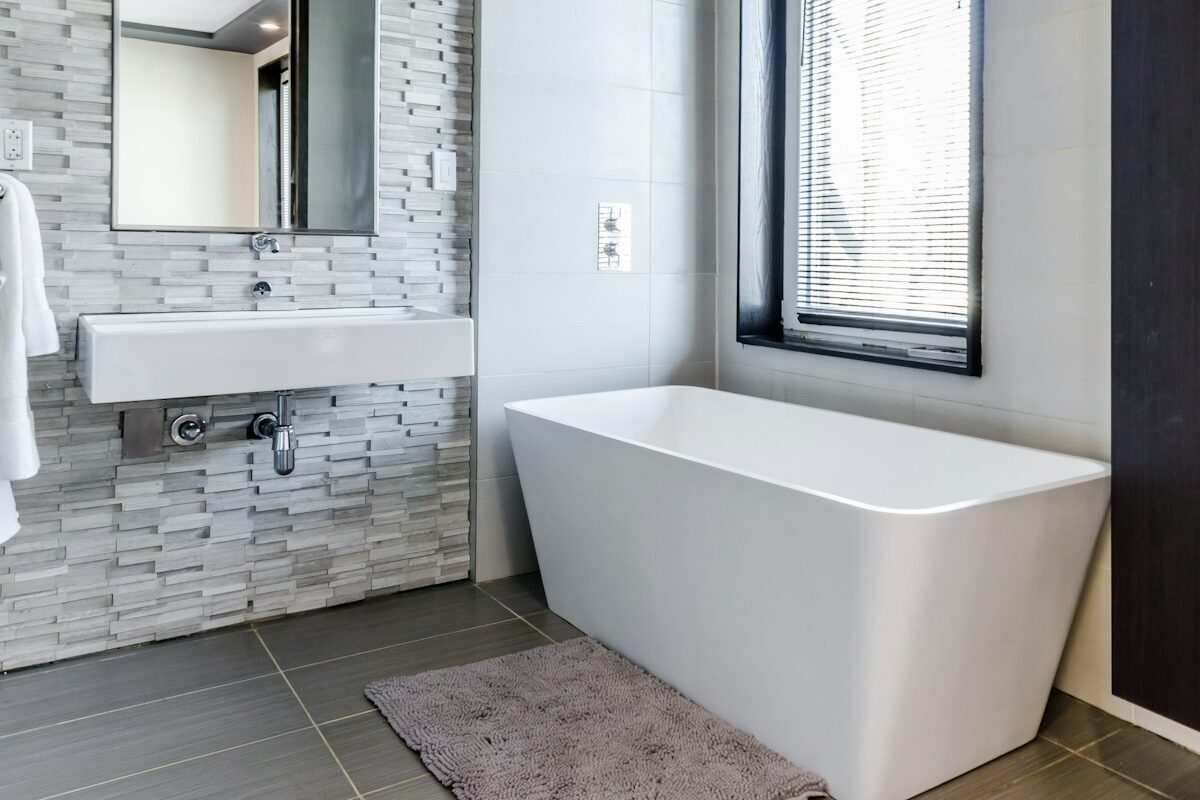 white ceramic bathtub near white framed window