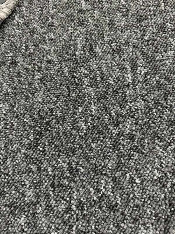 Close-up image of a textured gray carpet, Turbo 4m, with a loop-pile weave. The photo showcases the detailed and uniform surface of the carpet, highlighting its softness and the subtle variations in the shades of gray.